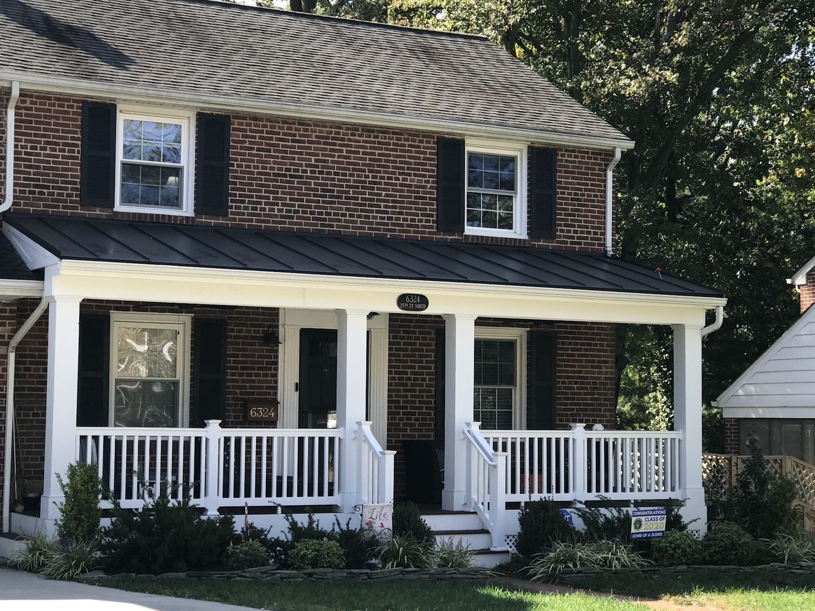 New covered front porch with white columns and railings on a brick colonial