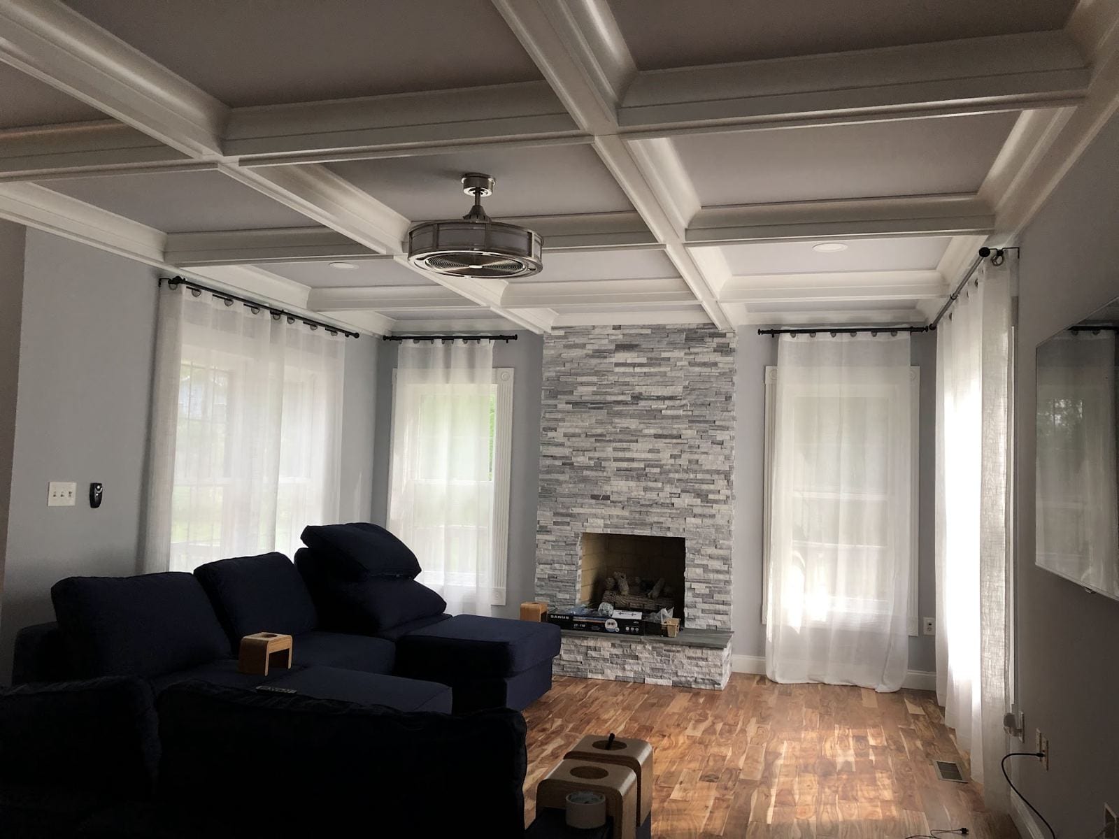 Family room addition with a coffered ceiling, stacked-stone fireplace and hardwood floor