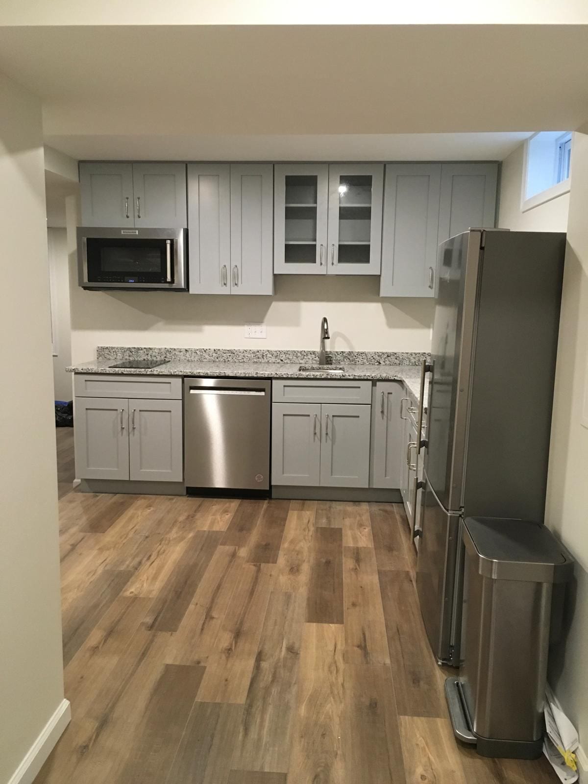 Basement kitchenette with gray cabinets, granite counters and stainless appliances