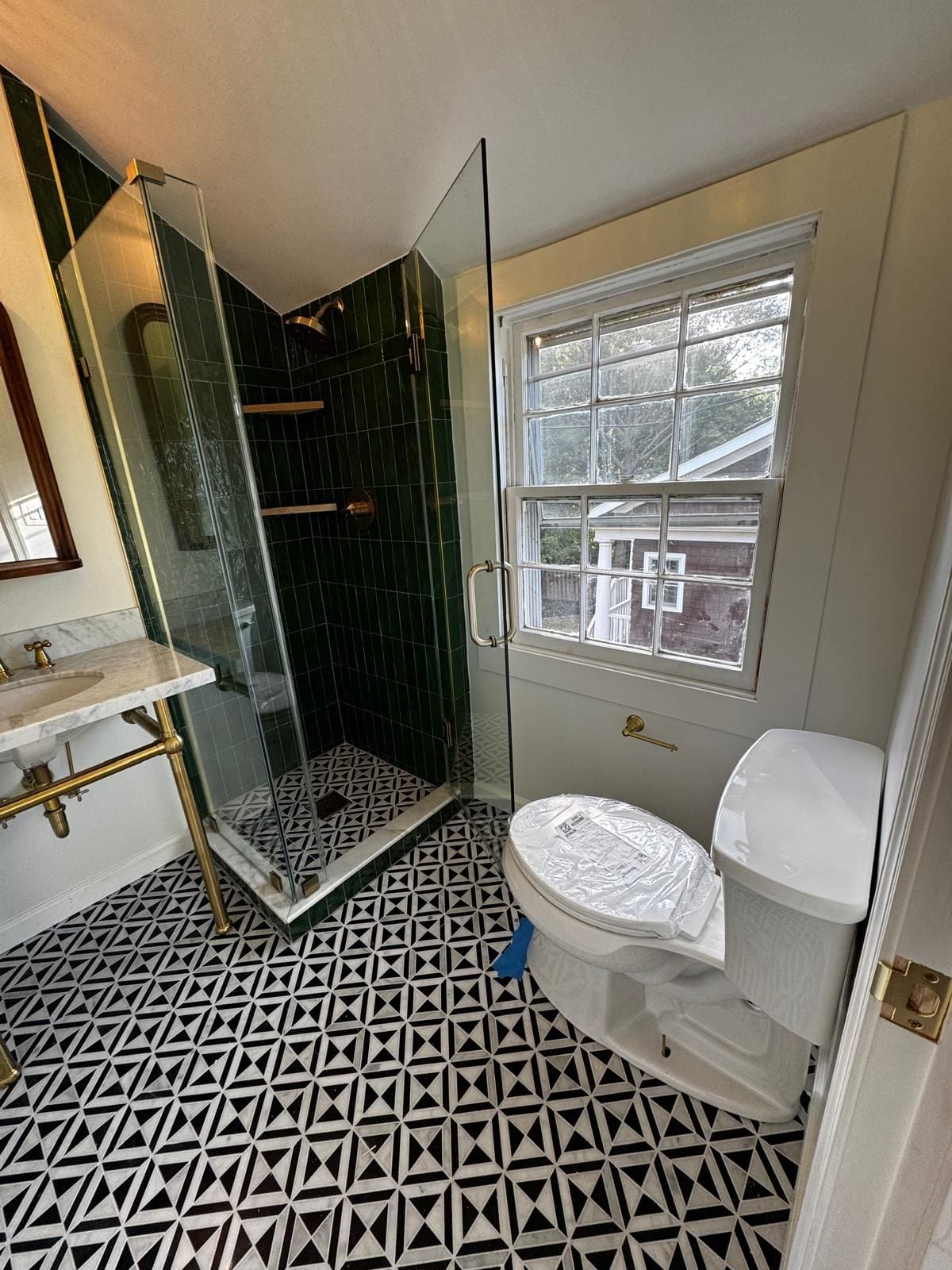 Bathroom in a new addition with a glass shower, console sink and black-and-white geometric floor