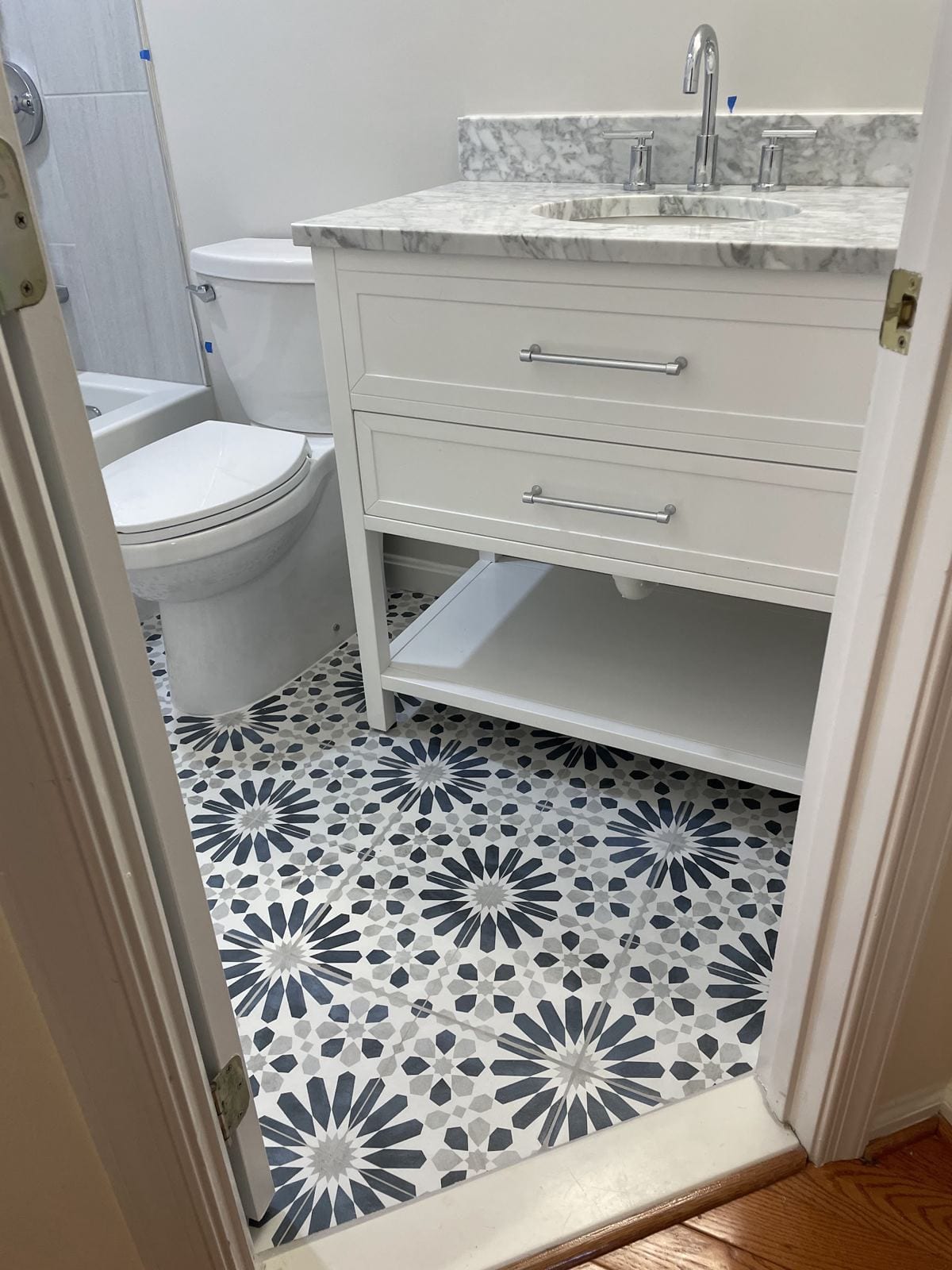 Bathroom vanity with a marble top over a patterned blue-and-white cement-look tile floor
