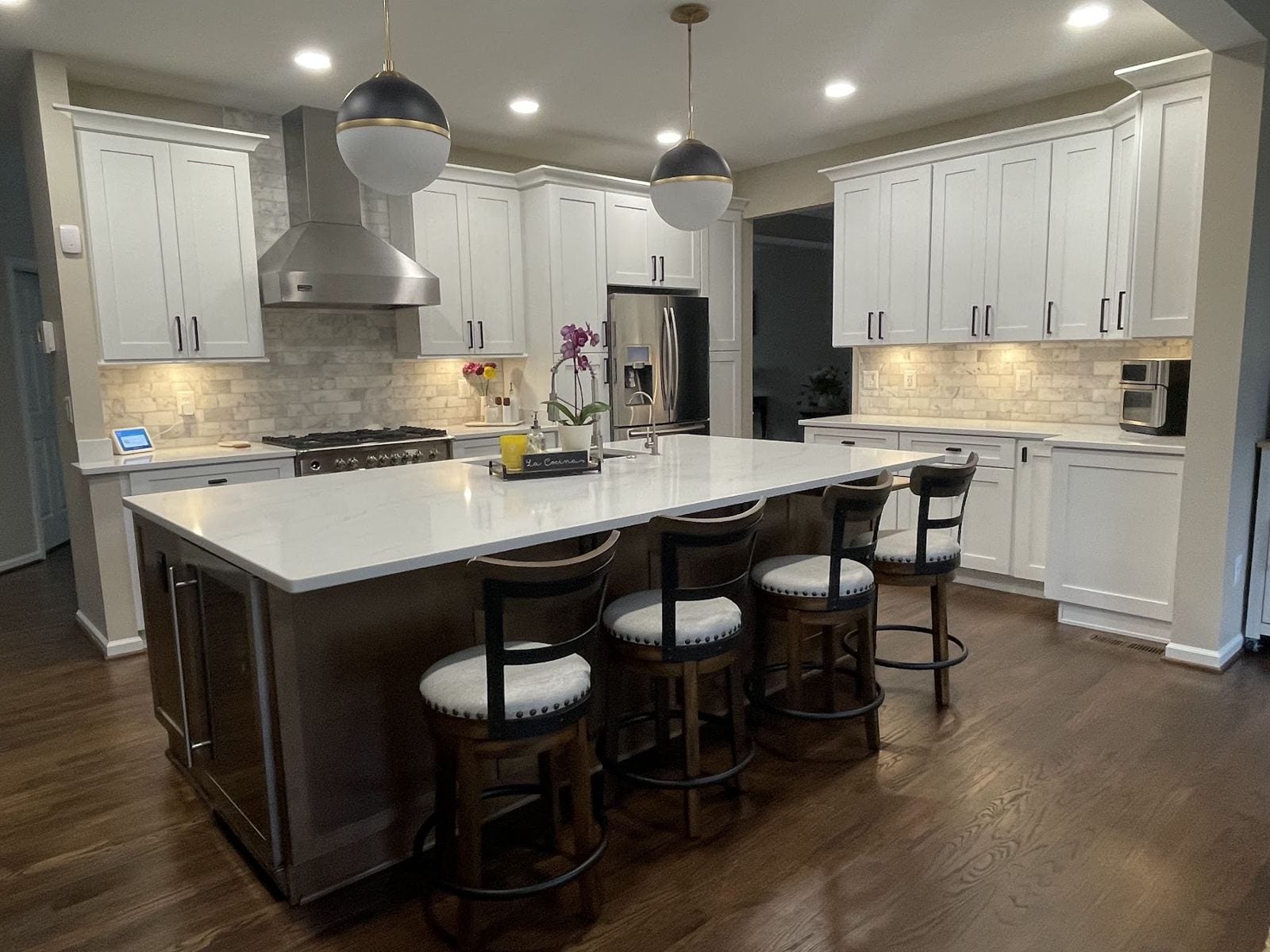 Remodeled kitchen with a quartz-topped walnut island, globe pendants and white shaker cabinets