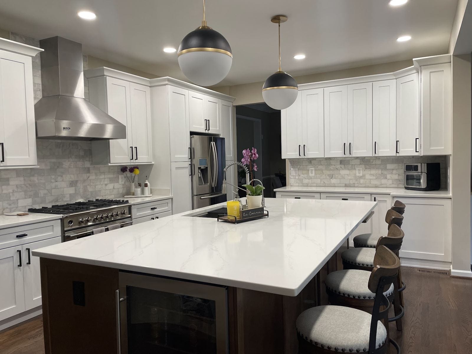 Kitchen remodel with a large quartz island, stainless range hood and marble backsplash