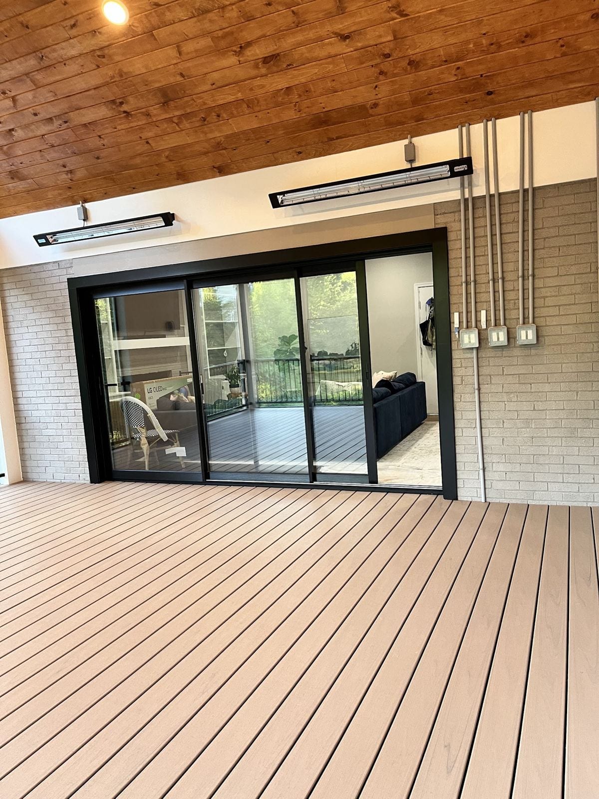 Sunroom addition with composite flooring and black sliding doors into the house