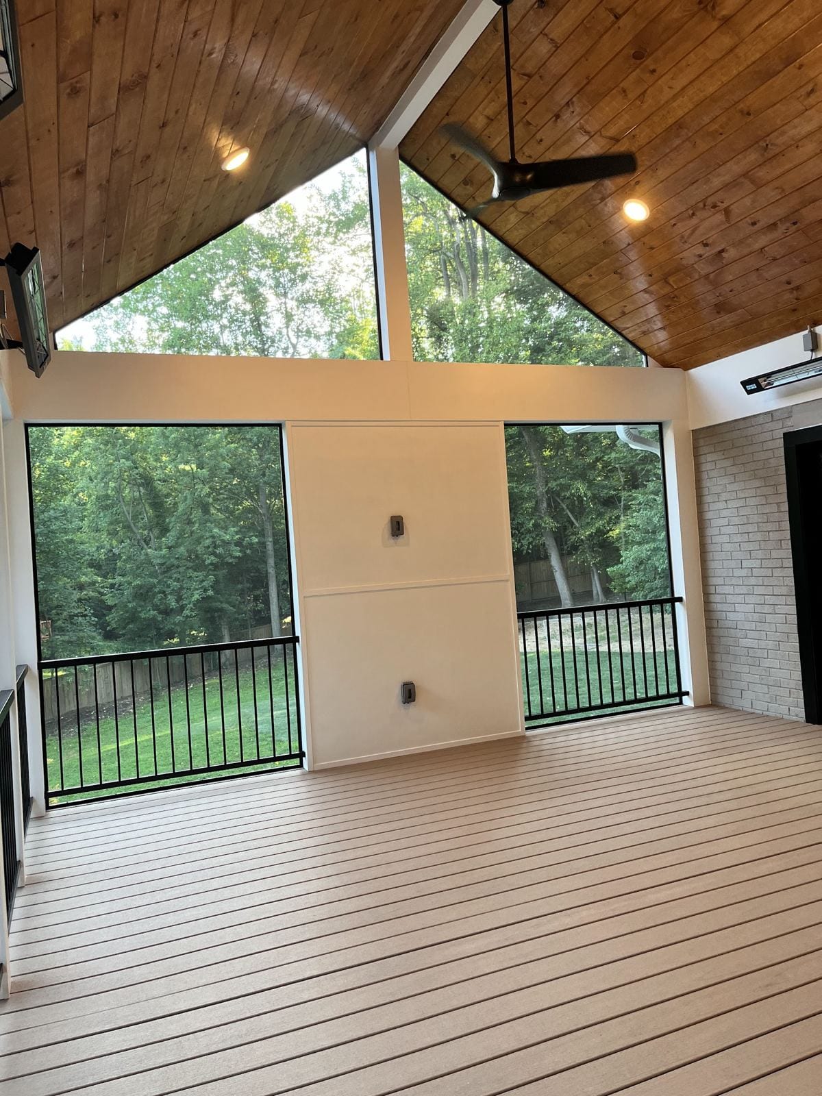Sunroom addition with a vaulted tongue-and-groove wood ceiling, composite floor and black railings