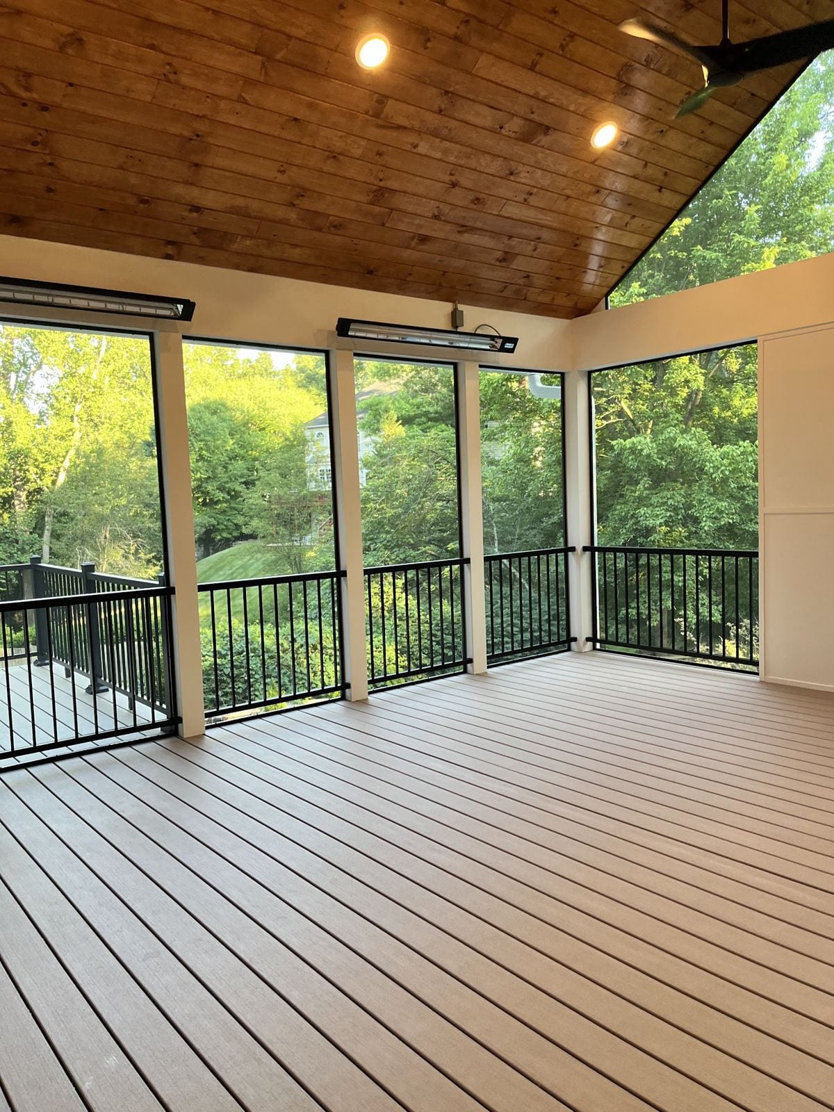 Sunroom addition with a wood ceiling, recessed lights and black aluminum railings