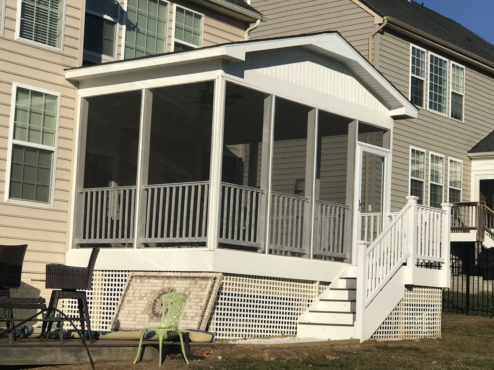 Screened porch addition with white railings and steps on the back of a two-story home